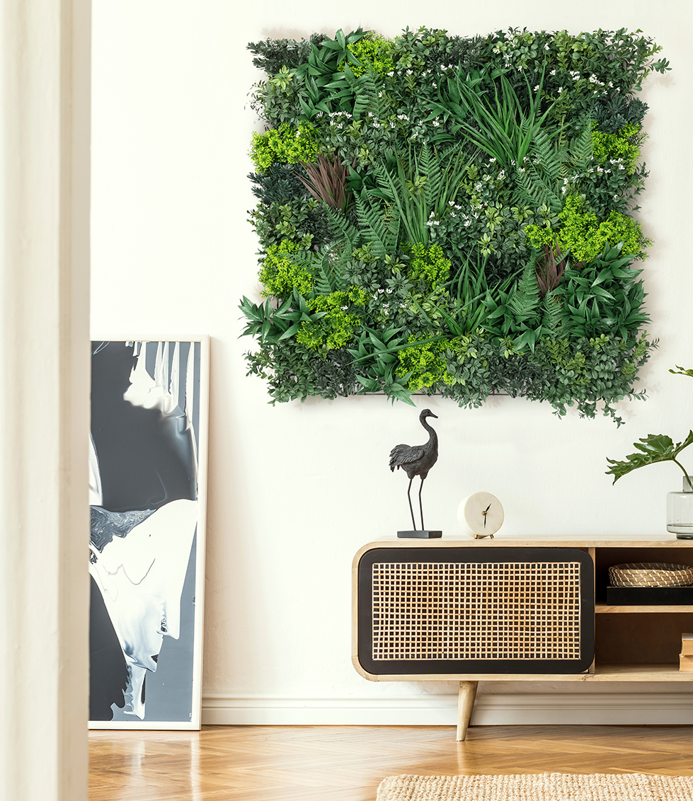 Plant wall on peach colored wall with a small statue on an armoir