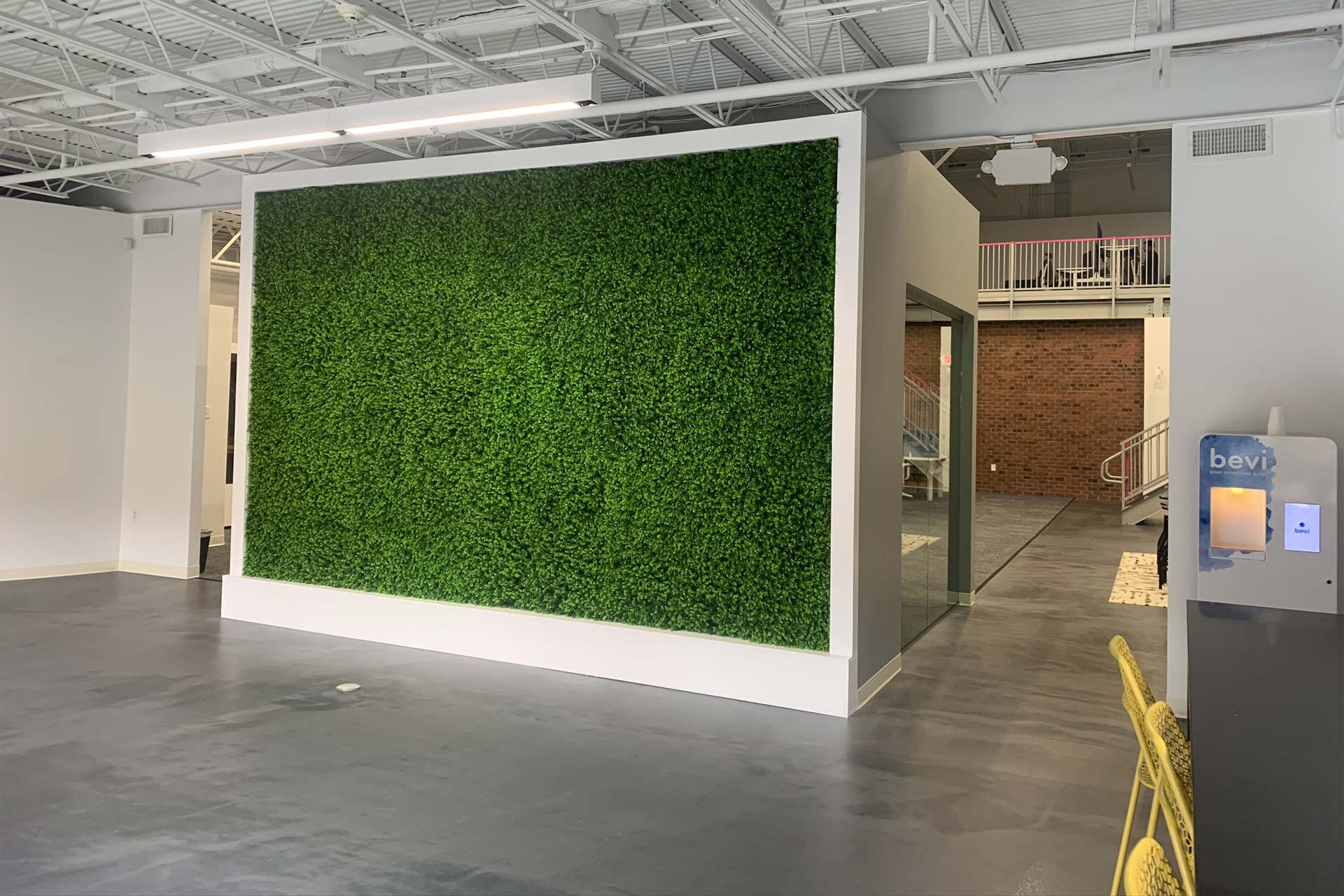 Office with plant wall and yellow desk chairs