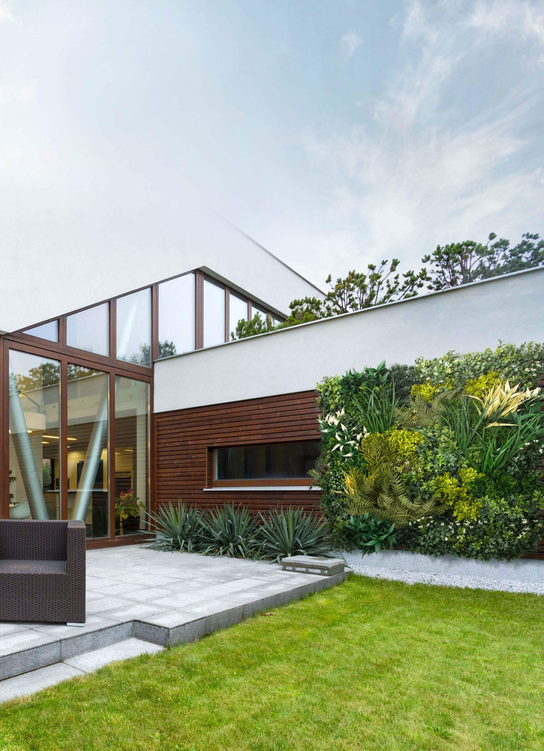 Beautiful exterior of a modern home with a plant wall facing a grass and cement area